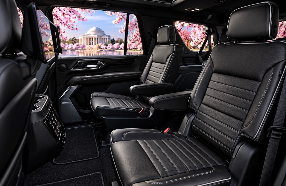 GMC Yukon Denali rear passenger cabin with black leather seats and cherry blossom view