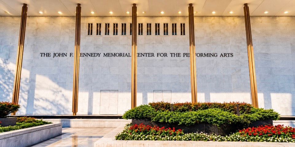 Kennedy Center exterior facade with gold columns and flower garden daytime