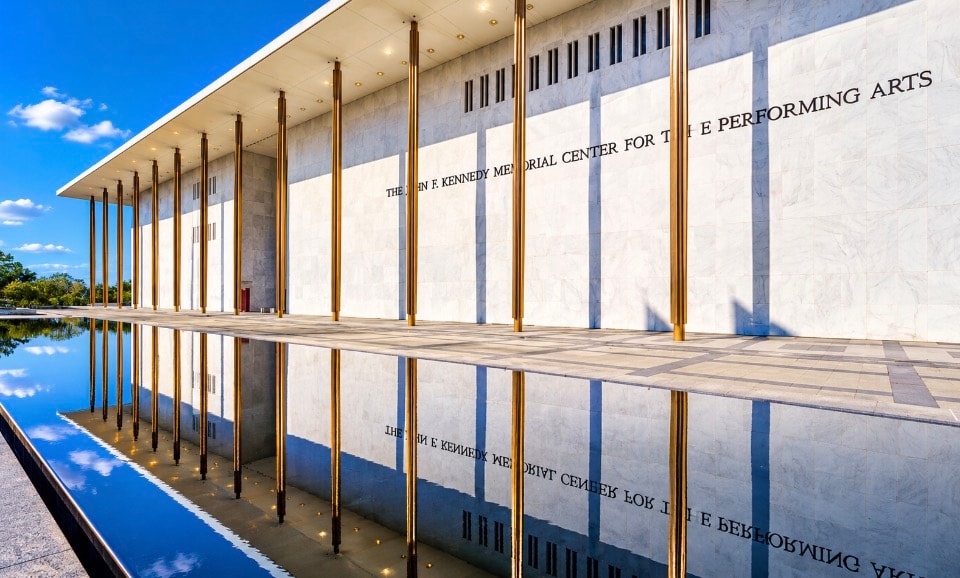 Kennedy Center exterior with gold columns reflecting in rooftop pool blue sky