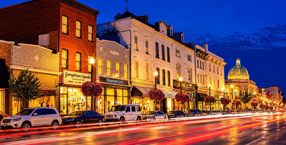 Georgetown DC M Street at night with light trails shops and dome in background